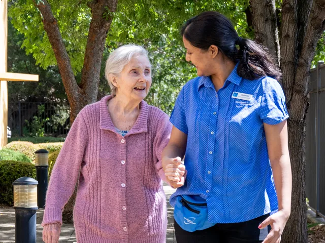 A staff member walking a resident while having a hat with her