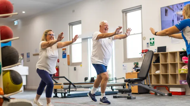  Name Female and Male Resident In Health & Fitness Centre Doing A Workout With Female Trainer At The Pines Retirement Living