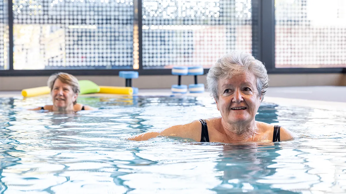 A group of female clients participating in an aqua fitness class designed to support joint mobility and social connection