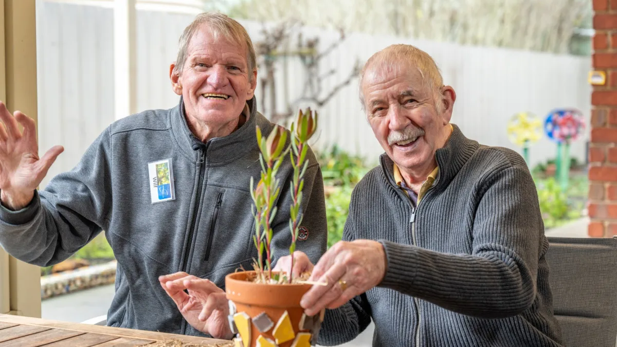 Two men with a plant in Willow Fern Cottage