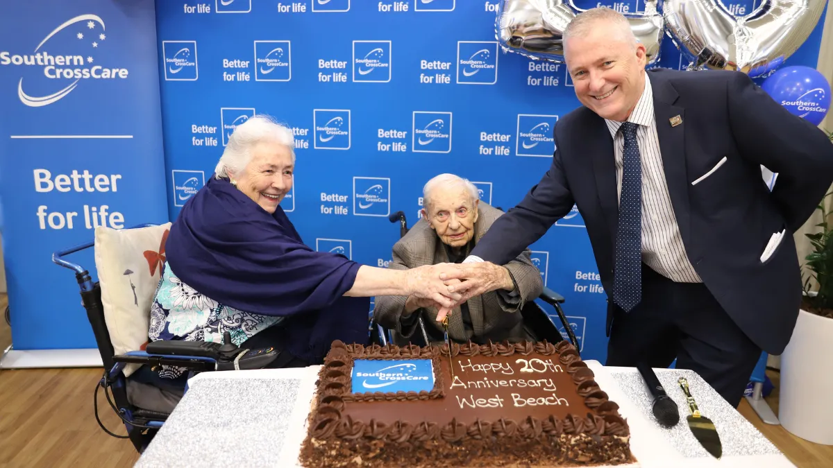 Residents Cathy and Norman cutting the cake with CEO David Moran