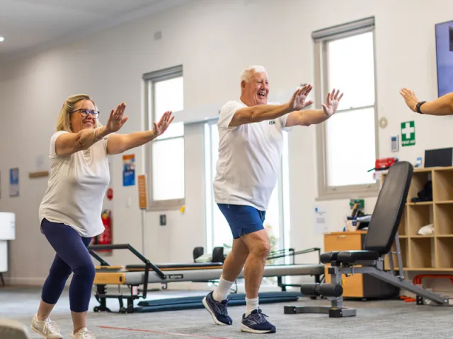 Name Female and Male Resident In Health & Fitness Centre Doing A Workout With Female Trainer At The Pines Retirement Living