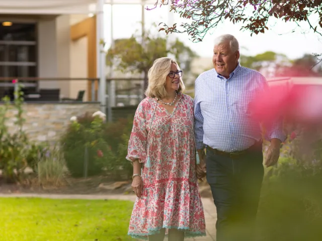 Female and Male Resident Walking Through Garden At The Pines Retirement Living