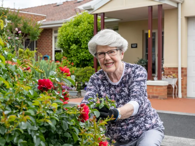Female Resident Picking Roses At Bedford Heights Estate Retirement Living
