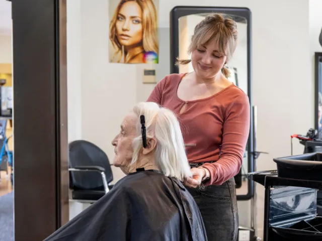 Female resident with hairdresser in salon 