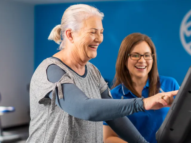 Health & Fitness Centre Trainer Assisting Client On Machine