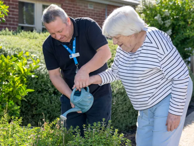Female Resident & Male Staff Member Outside In Garden At Mount Carmel Residential Care