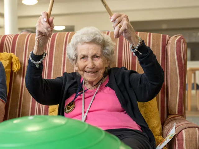 Female Resident Fit Ball Drumming At Mount Carmel Residential Care