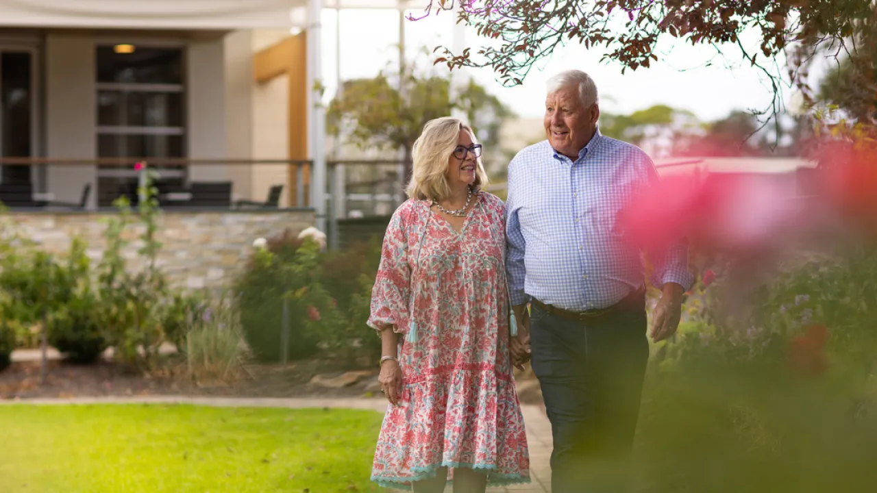 Female and Male Resident Walking Through Garden At The Pines Retirement Living