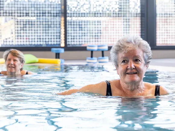 A group of female clients participating in an aqua fitness class designed to support joint mobility and social connection