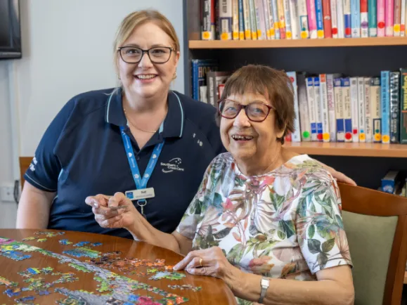 Female Resident and Staff Member Solving A Jigsaw Puzzle At The West Beach Residential Care