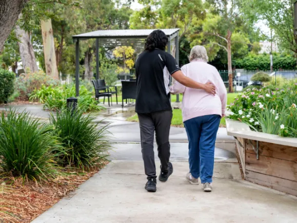 Female Resident and Allied Health Staff Member Walking Through Garden At Fullarton Residential Care