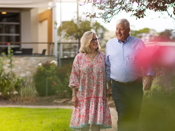 Female and Male Resident Walking Through Garden At The Pines Retirement Living