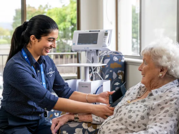 Female Registered Nurse Measuring A Female Resident's Blood Pressure At Southern Cross Care Residential Care Home