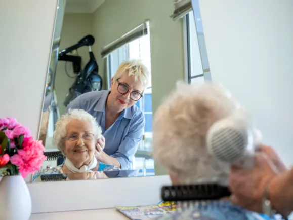 Female Resident Having Her Hair Blowdried By Female Hairdresser At Southern Cross Care Residential Care Home