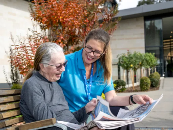 Female Resident and Female Volunteer Reading Newspaper Together At Carmelite Residential Care