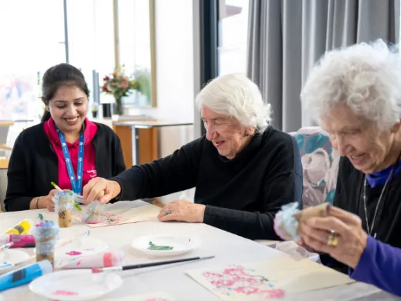 Two Female Residents and Female Lifestyle Staff Member Doing Arts and Crafts Activity Together At Carmelite Residential Care