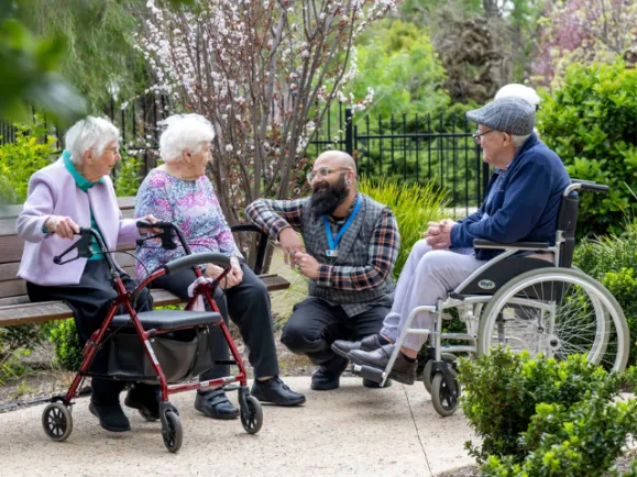 Southern Cross Care lifestyle assistant with 3 residents sitting outside