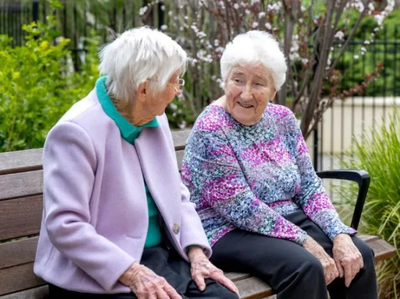 Two female residents sitting together outside